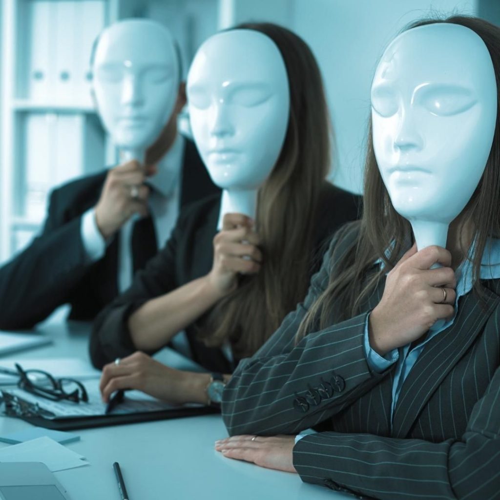 People sitting at table holding white masks on their faces to prevent others from seeing who they are.