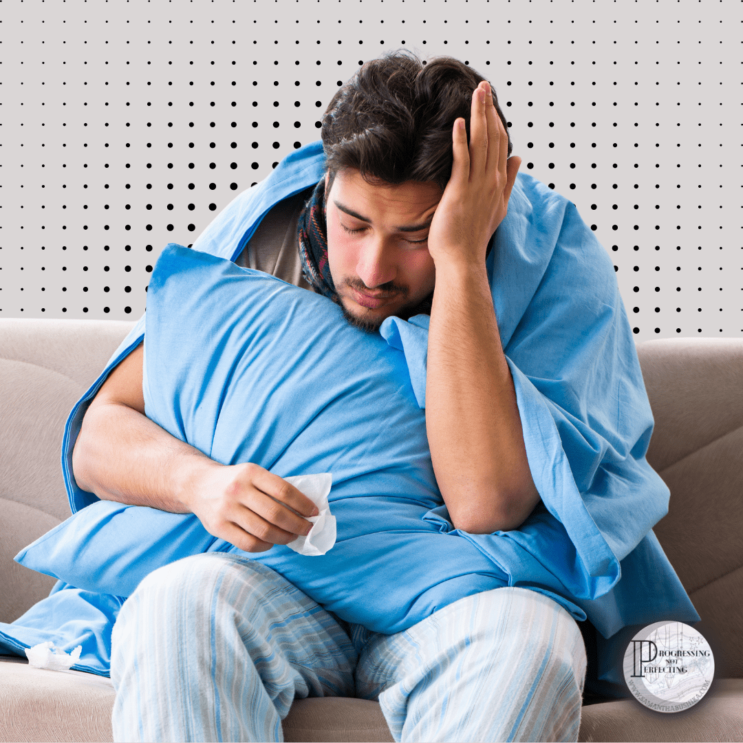 A Man Sitting On A Couch With A Blanket Covering His Face