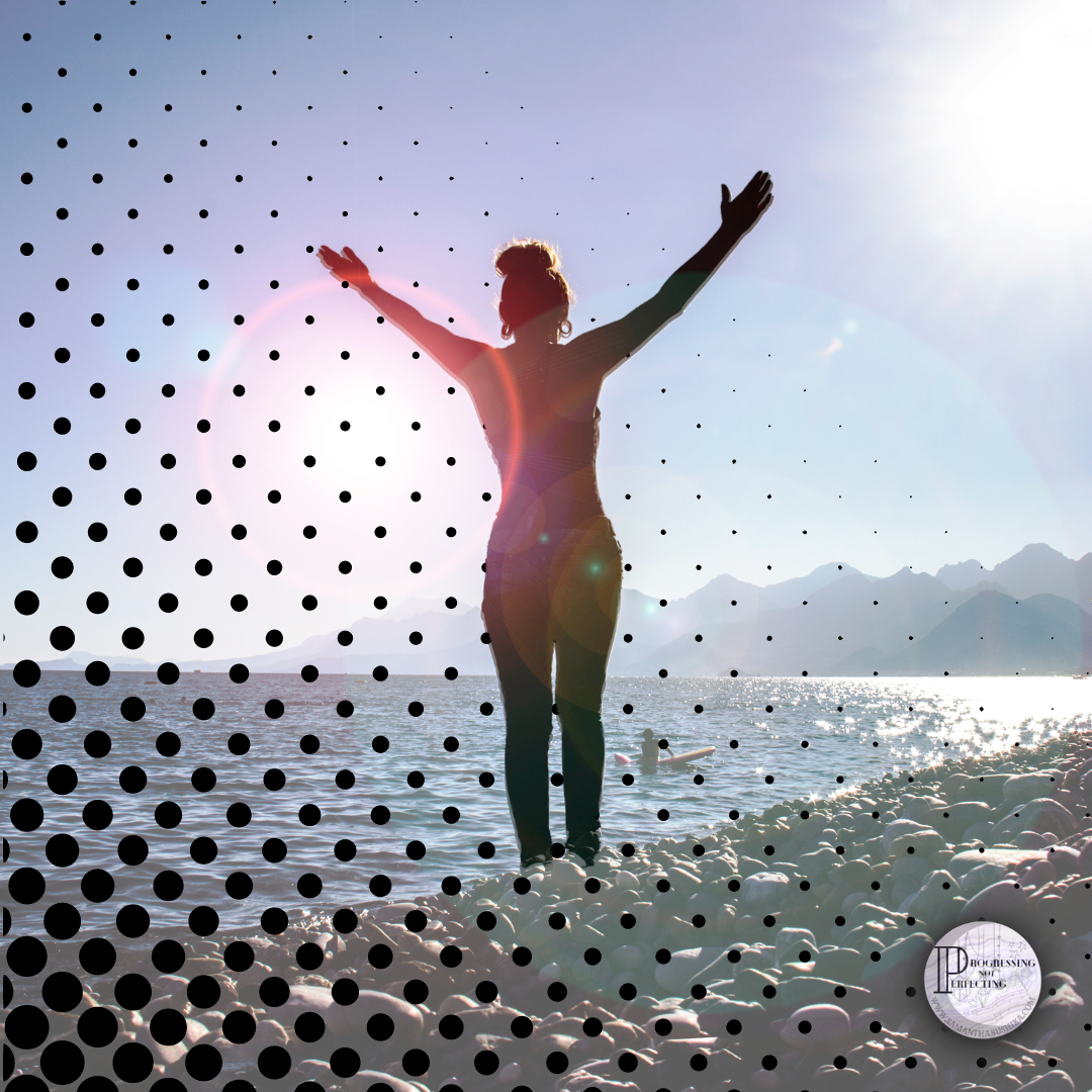 a woman standing on a beach with her arms raised